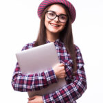 Young smiling confident woman using laptop computer and looking camera isolated over white